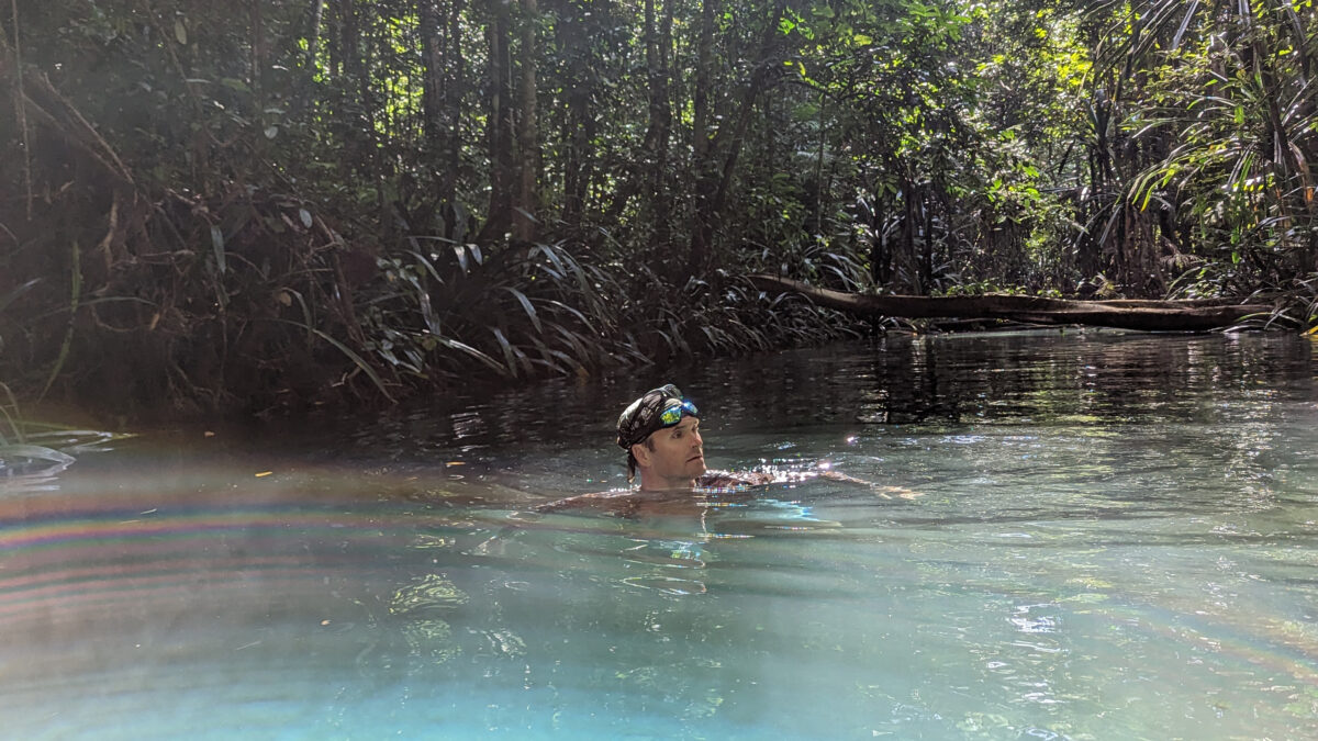 Rhett Butler swimming across a river in New Guinea.